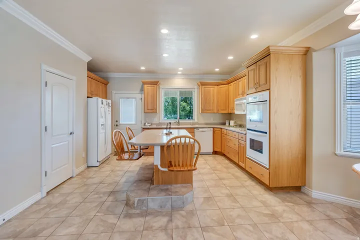 Kitchen featuring wood-finish cabinetry, tile flooring, recessed lighting, and a built-in double oven