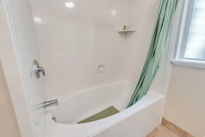 Bathtub with integrated shower surround, corner shelf, and wall-mounted fixtures