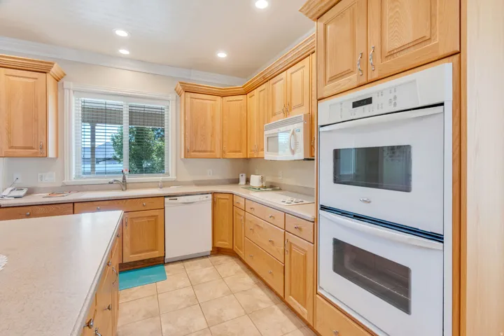 Kitchen featuring wood cabinetry, light-toned countertops, a double wall oven, and a built-in microwave