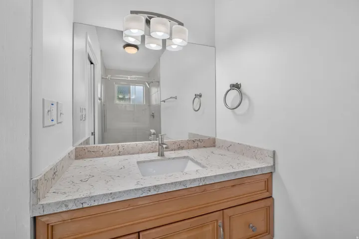 Vanity with wood-finish cabinetry, light-colored countertop, and an integrated rectangular sink