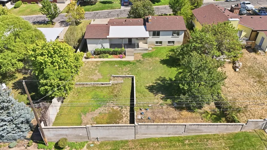 Expansive exterior featuring a terraced yard, mature trees, and a concrete perimeter fence