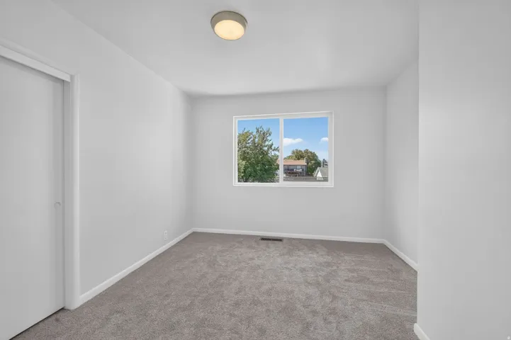 Neutral wall finishes, recessed lighting, carpet flooring, a white-framed window, and a white closet door