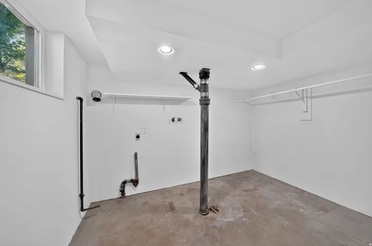 Recessed ceiling lighting, concrete flooring, window with exterior view, and wall-mounted shelving