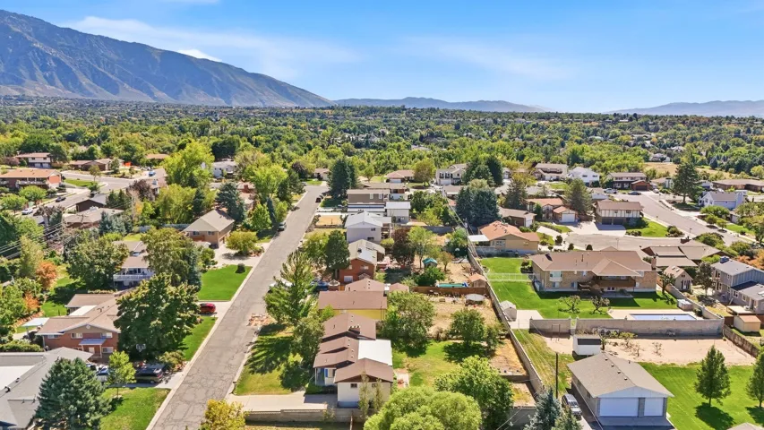 Residential neighborhood with mature trees, mountain backdrop, and a private swimming pool