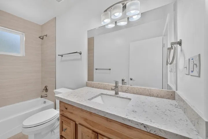 Wood-finish vanity with a light-toned countertop, undermount sink, and brushed nickel faucet