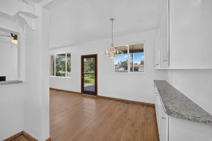 Wood-finish flooring throughout, white cabinetry with silver hardware, and stone countertops