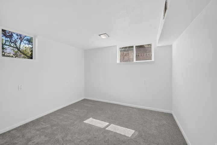 Recessed lighting fixture, plush grey carpeting, and two windows