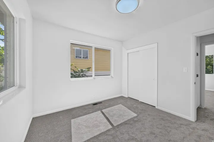 Recessed circular ceiling light, white walls, gray carpeting, dual pane windows, and a sliding closet door