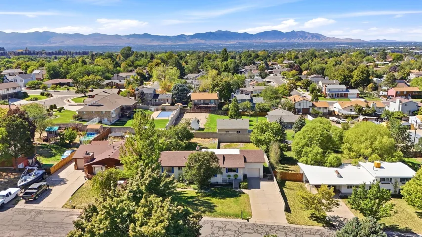 Expansive suburban setting with established landscaping, varied rooflines, and distant mountain scenery