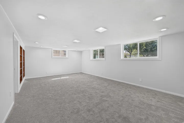 Spacious room featuring light gray carpeting, recessed ceiling lighting, and multiple windows