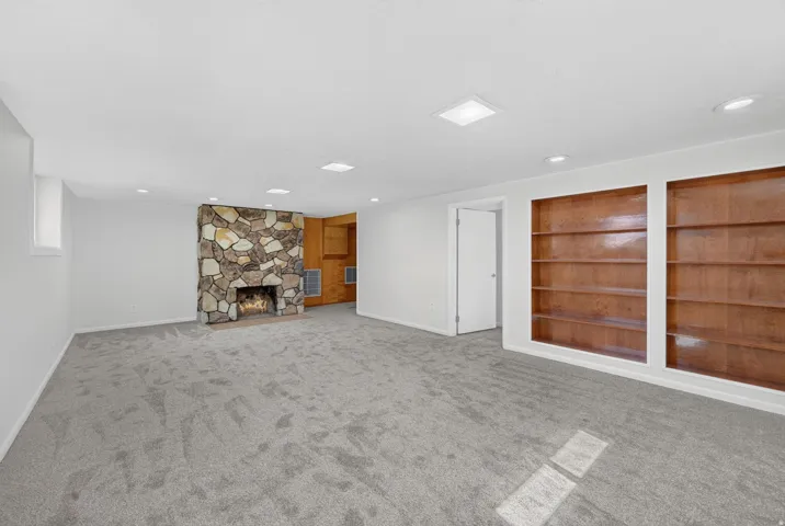 Stone-clad fireplace feature with built-in wood shelving and recessed lighting