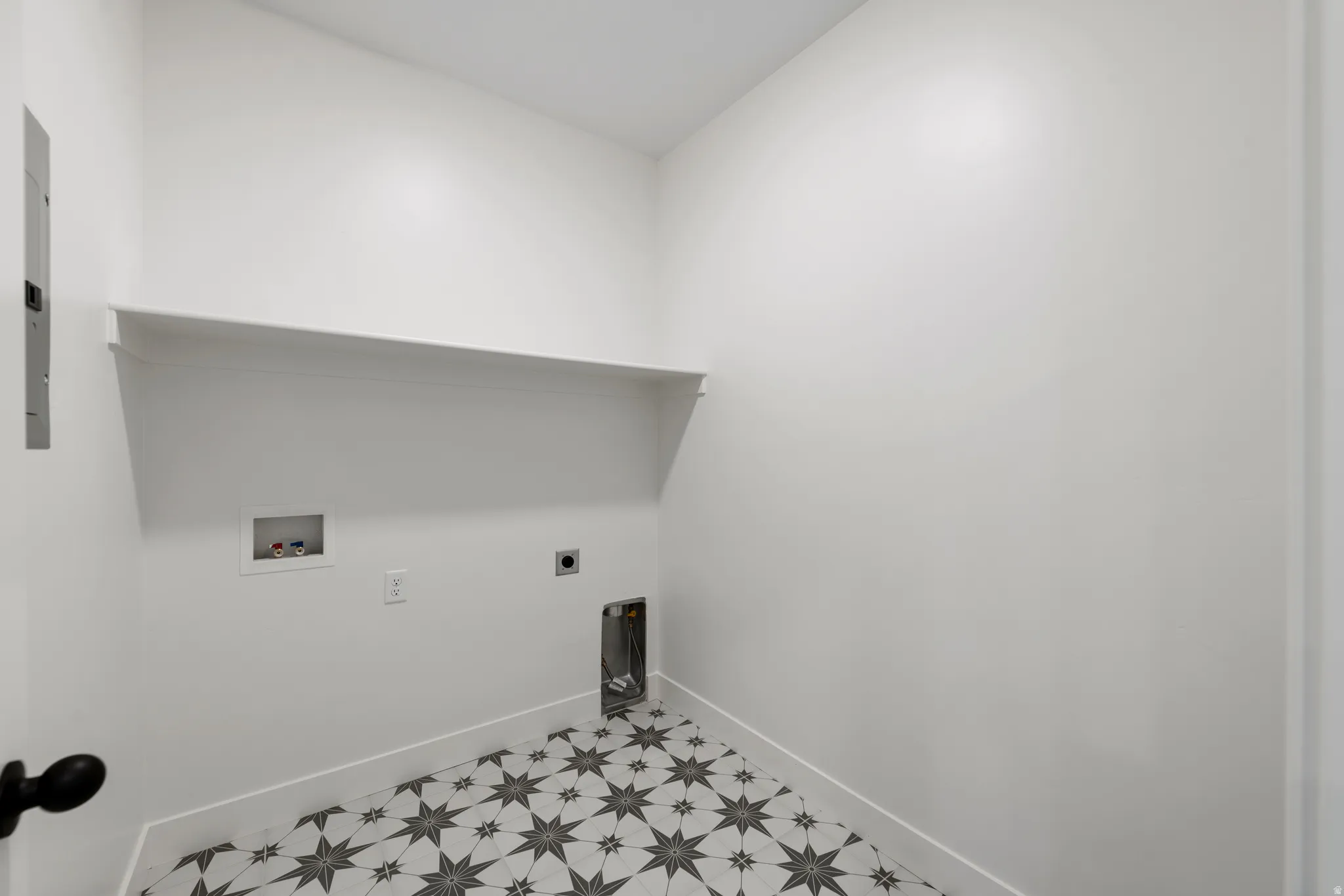 Utility space featuring a geometric star-patterned tile floor and an integrated wall shelf