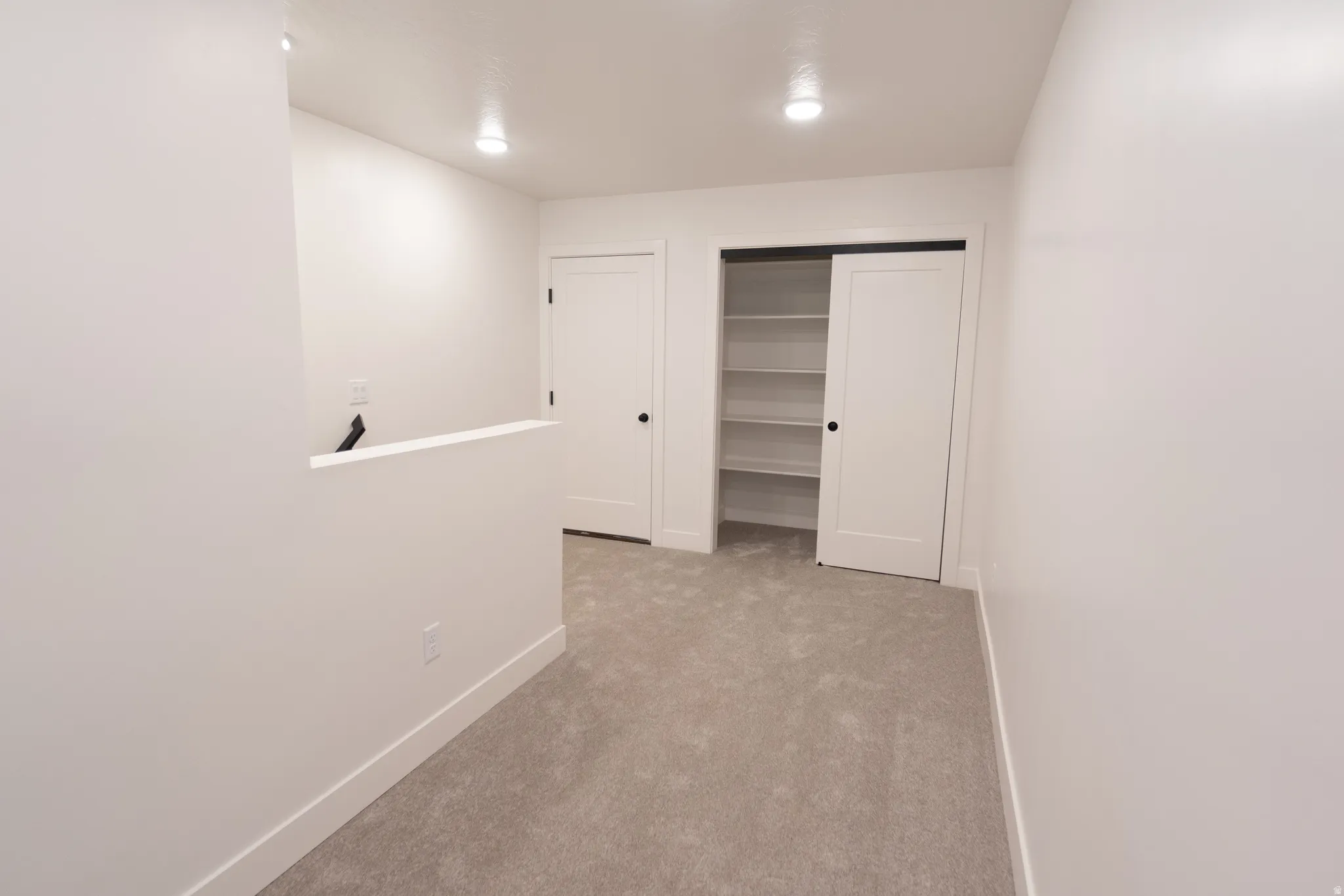 Recessed lighting, light gray carpet flooring, white walls, built-in shelving, and white interior doors