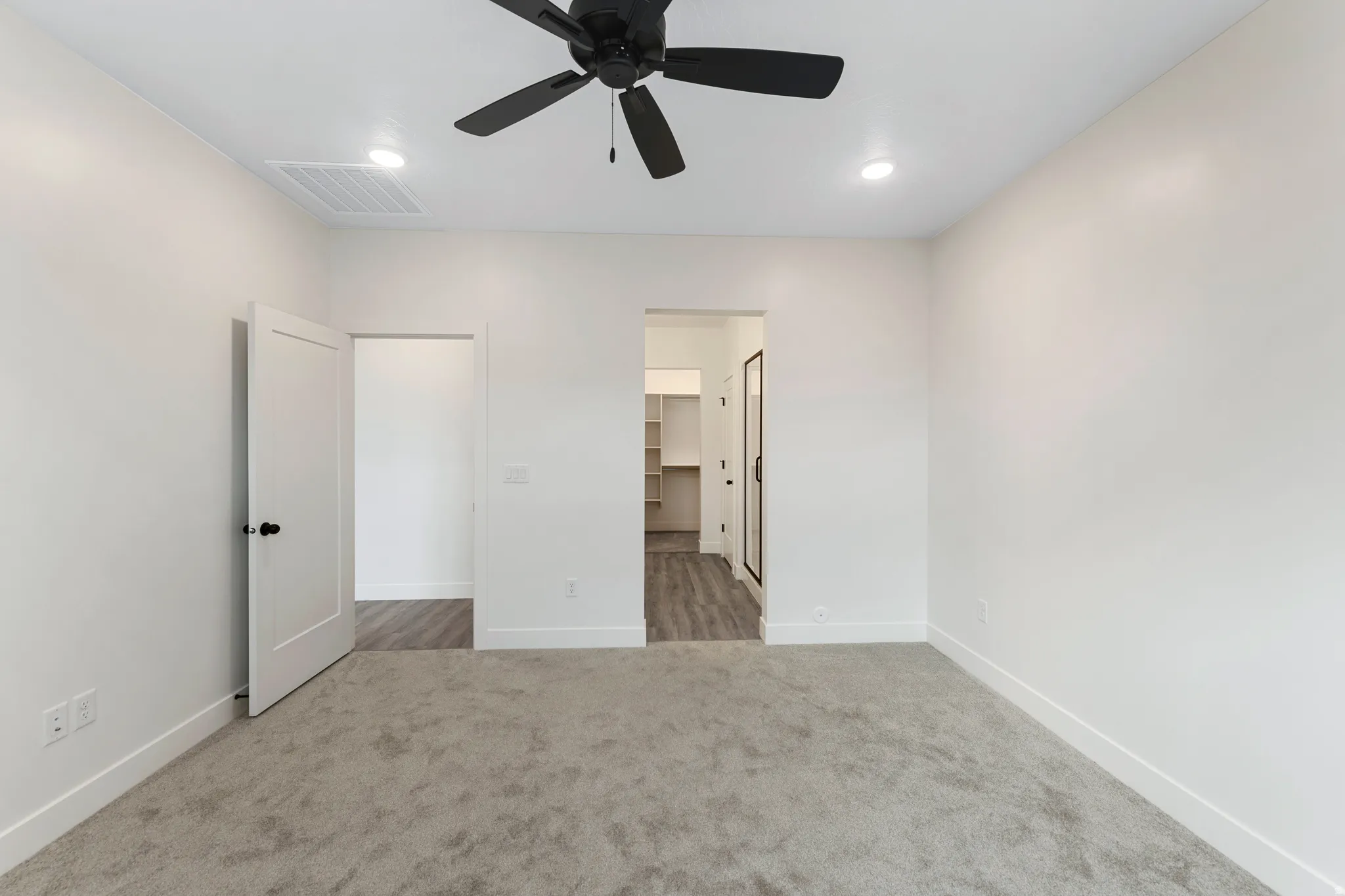 Recessed lighting, ceiling fan with black finish, light gray carpeting, white interior doors, and wood-finish flooring in adjacent spaces