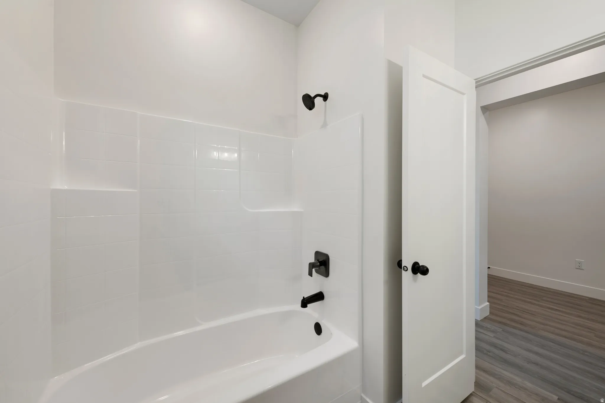 Bathtub with white tile surround and matte black fixtures