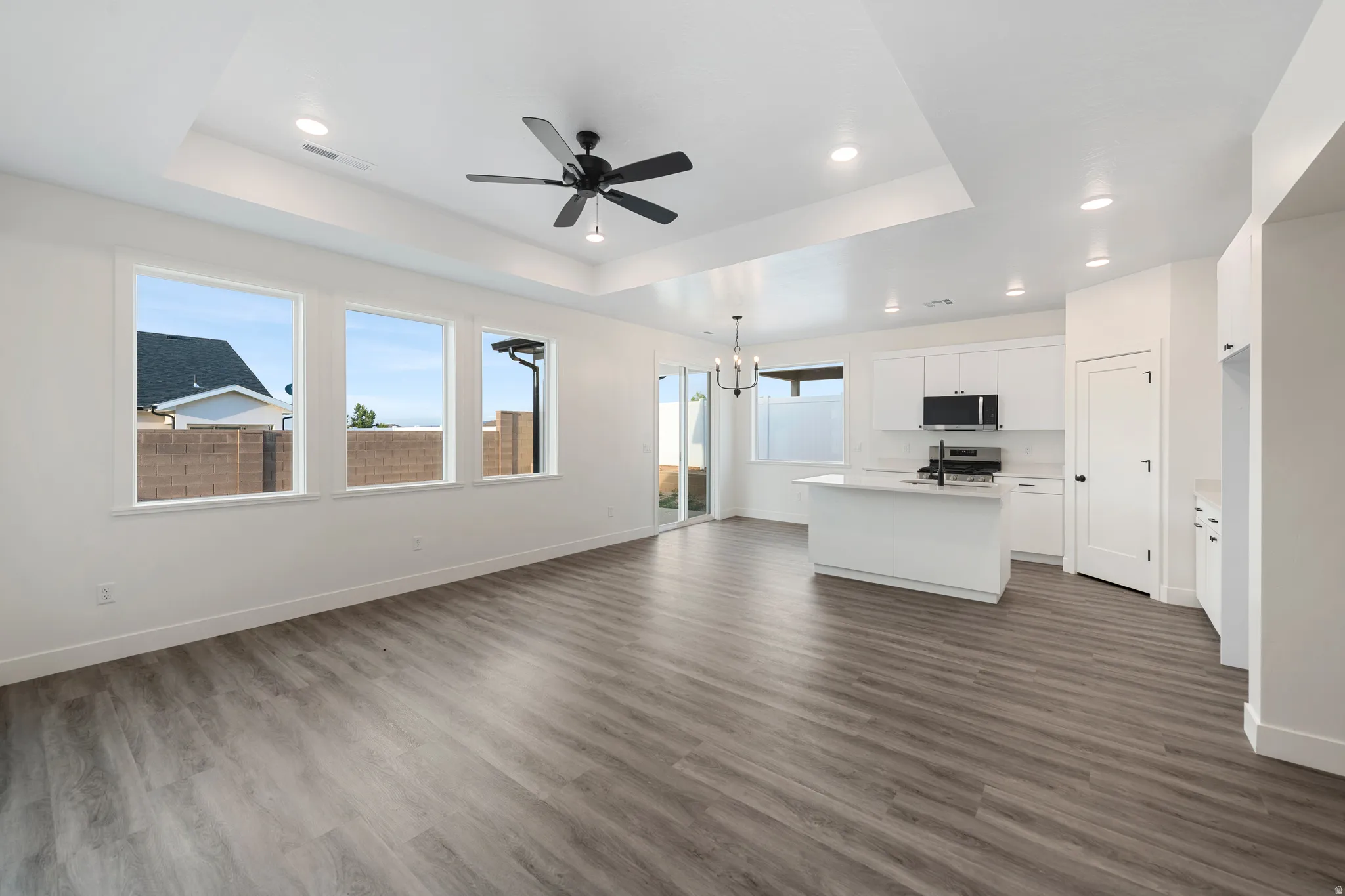 Open-concept living space featuring wood-finish flooring, recessed lighting, and a white kitchen with an island