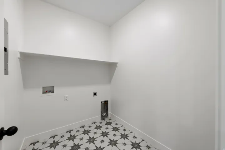 Utility space featuring a geometric star-patterned tile floor and an integrated wall shelf