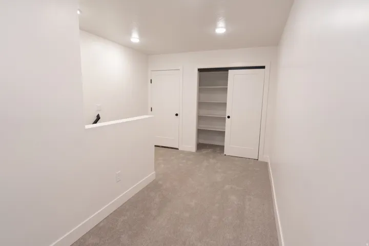 Recessed lighting, light gray carpet flooring, white walls, built-in shelving, and white interior doors
