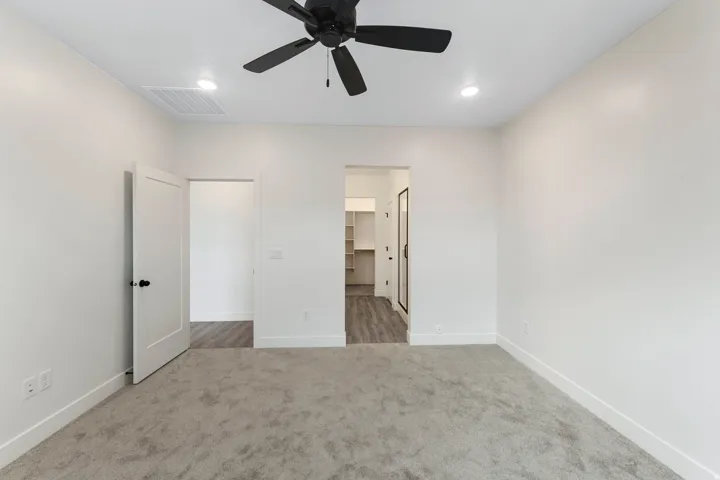 Recessed lighting, ceiling fan with black finish, light gray carpeting, white interior doors, and wood-finish flooring in adjacent spaces
