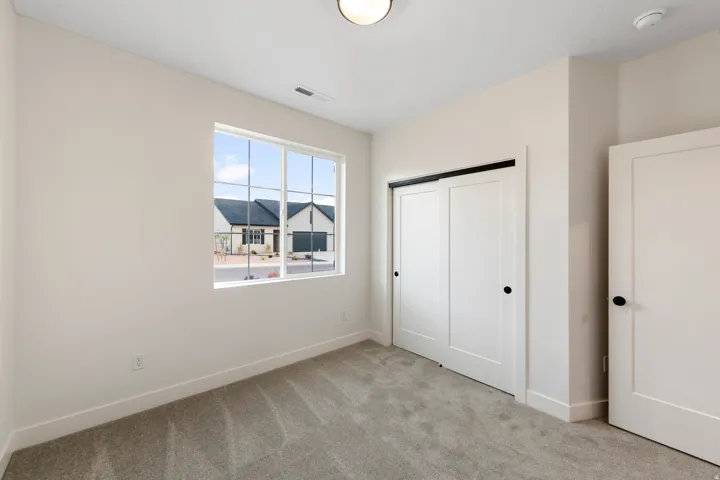 Neutral paint palette with a bright window, textured carpet flooring, and white paneled doors