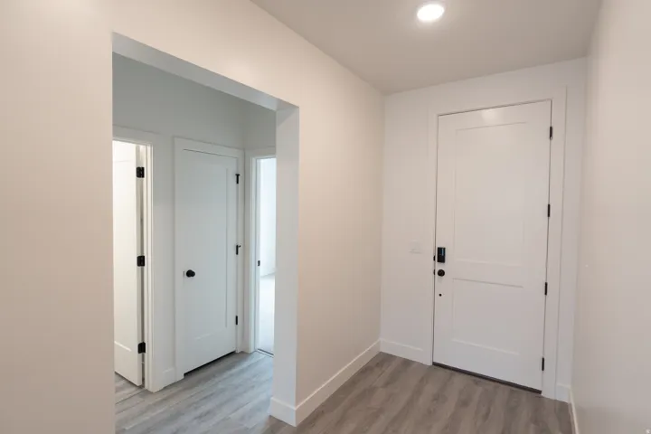 Entryway with wood-finish flooring, recessed lighting, and white paneled doors with matte black hardware