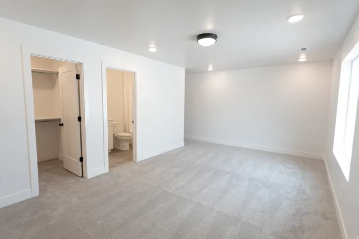 Recessed lighting, flush mount ceiling fixture, window with natural light, neutral carpeting, and a built-in closet with shelving