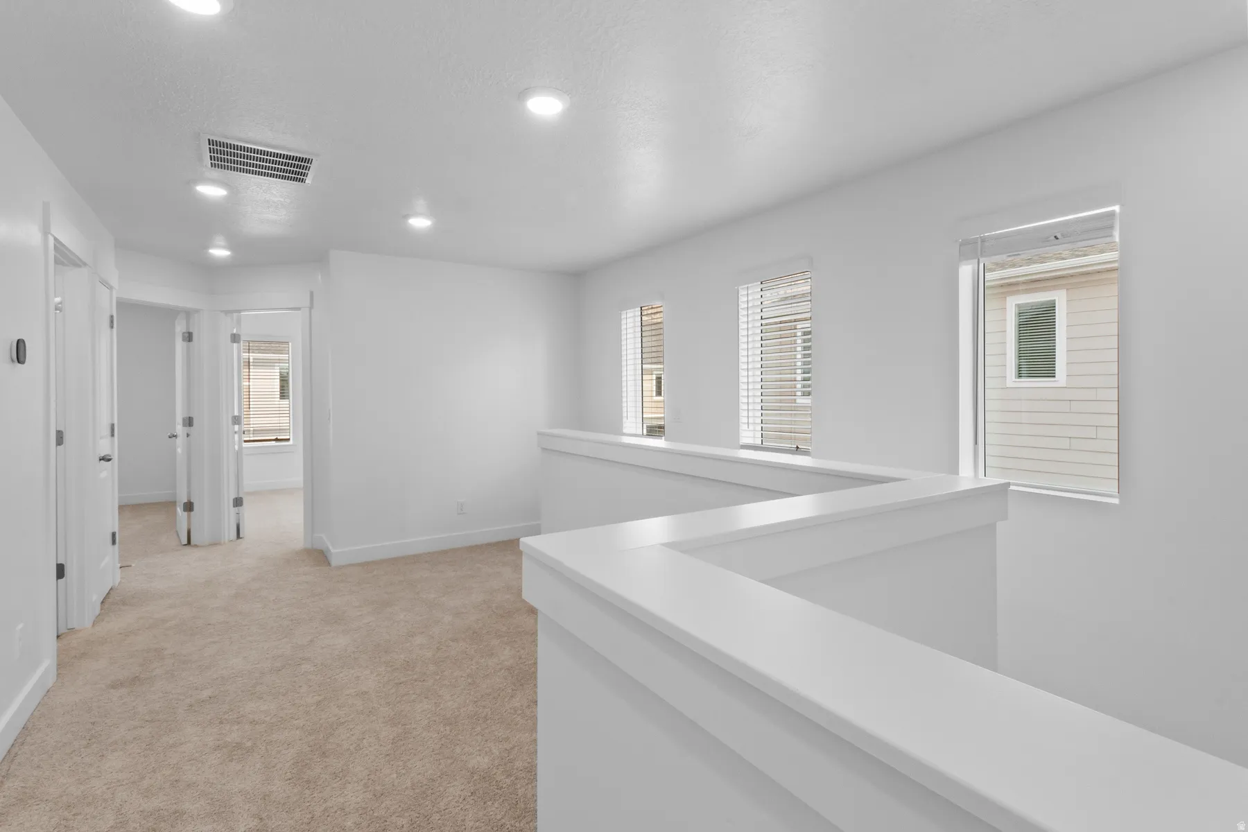 Carpeted flooring extending throughout, multiple windows with blinds, recessed lighting, and white paneled interior doors