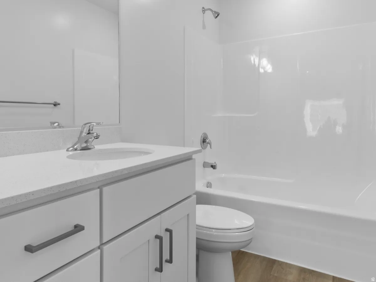 White vanity with dark hardware, a single basin sink, and light-toned countertop