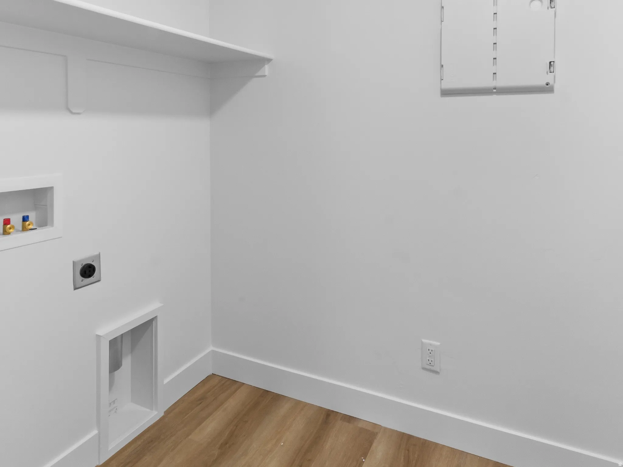 Laundry area featuring wood-finish flooring, white walls, and built-in shelving