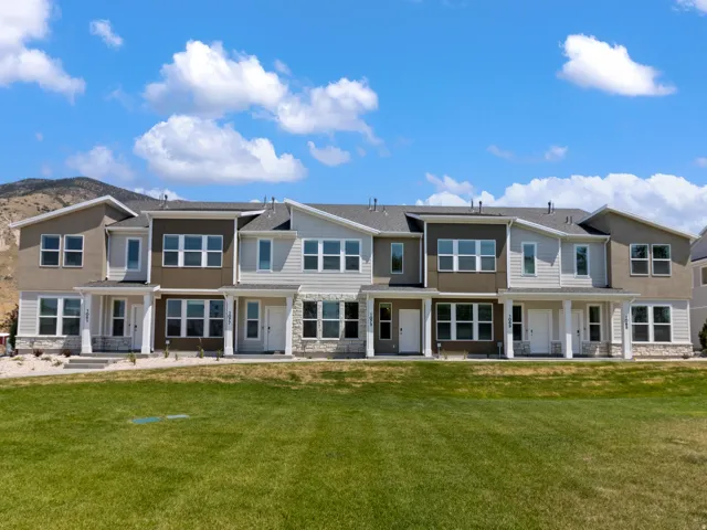 Multi-story residences featuring varied façade treatments, covered front entryways, and a manicured lawn