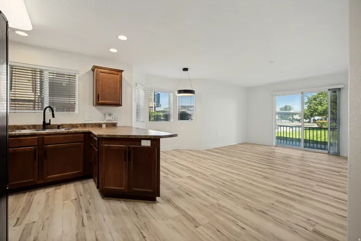 Open-concept living area featuring wood-finish flooring, recessed lighting, and a sliding glass door to an outdoor balcony
