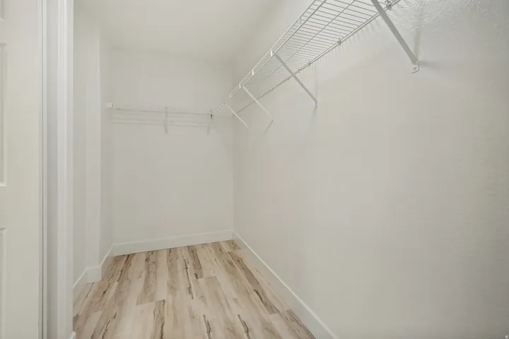 Walk-in closet featuring wood-finish flooring, white wire shelving, and crisp white walls