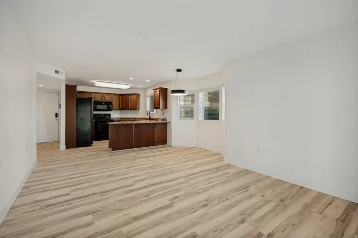 Open-concept living area with wood-finish flooring, a kitchen island, dark wood cabinetry, and a bay window