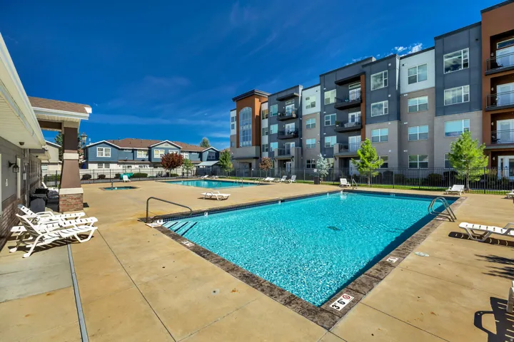 Outdoor swimming pool with concrete decking, surrounding multi-story buildings, and visible balconies