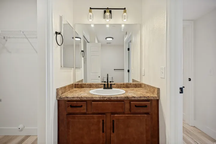 Vanity with a round undermount sink, a countertop featuring a stone-like finish, and a dark wood-finish cabinet with black hardware