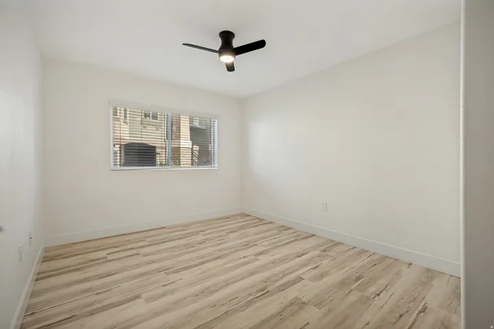 Wood-finish flooring, white walls, and a contemporary ceiling fan