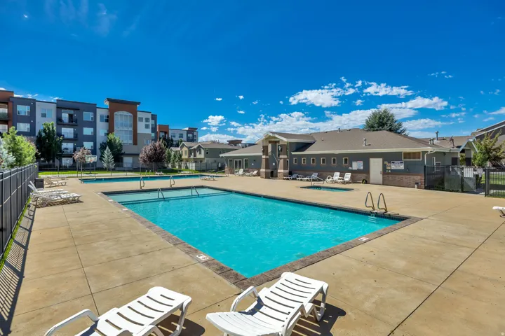 Expansive outdoor swimming pool with surrounding concrete decking, and fenced perimeter