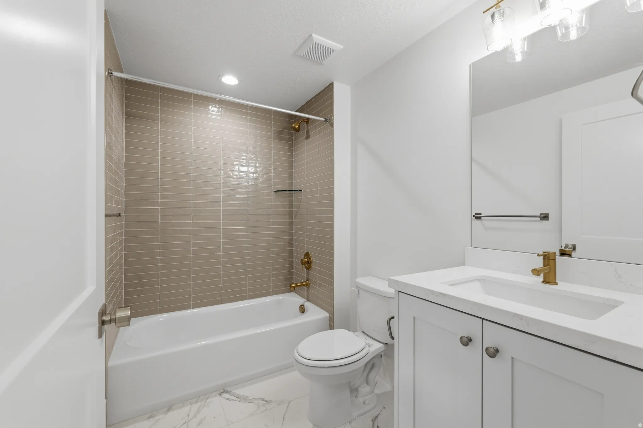 Basement bedroom with ensuite bathroom. White vanity with a rectangular undermount sink, brass faucet, and matching light fixture