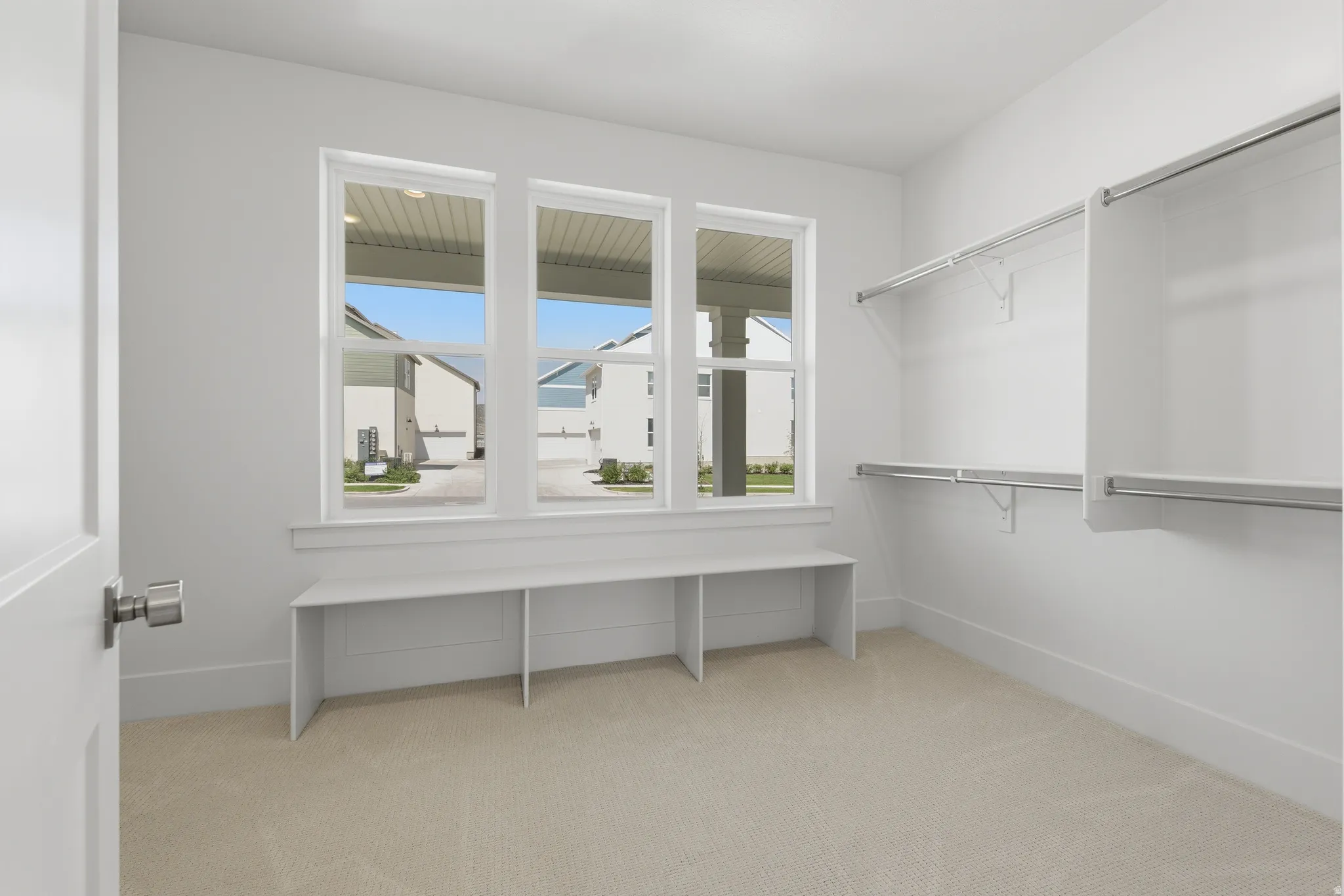 Primary Suite. Carpeted room with multiple windows, a built-in bench, and built-in closet shelving