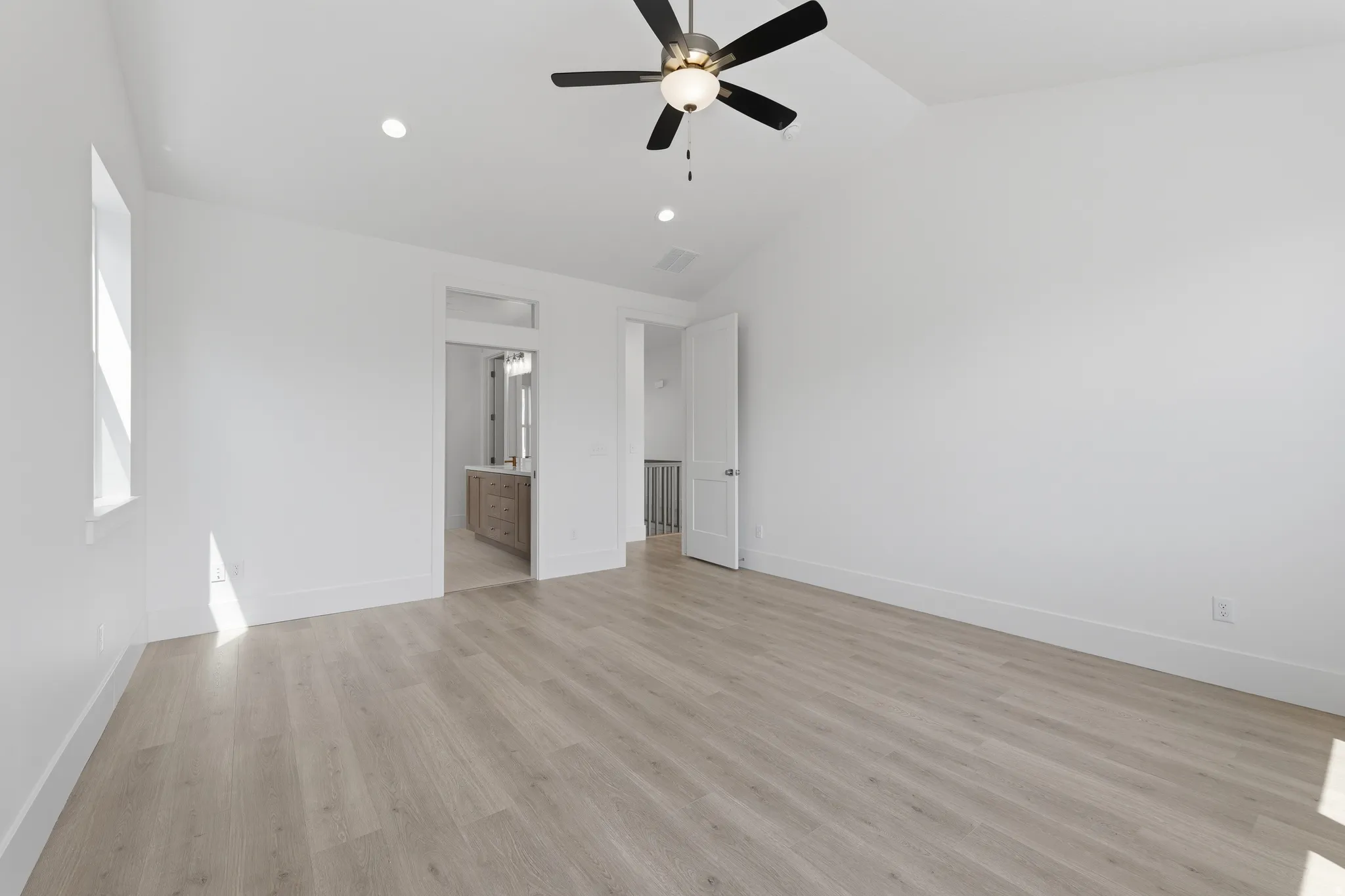 Primary Suite. Vaulted ceiling with a ceiling fan, recessed lighting, wood-finish flooring, and a large window