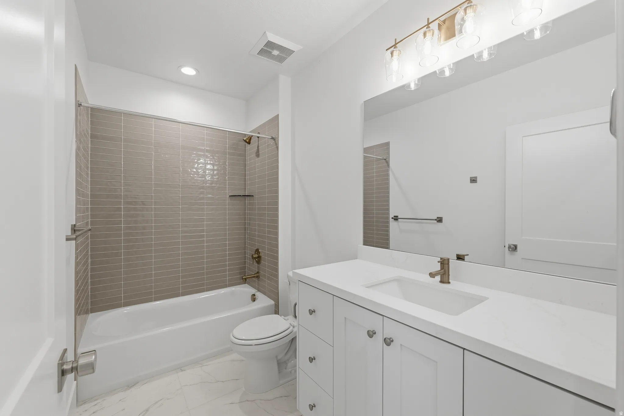 Full bathroom featuring a white vanity with integrated sink, a large mirror, a bathtub with a tiled shower surround, and a ceiling-mounted light fixture