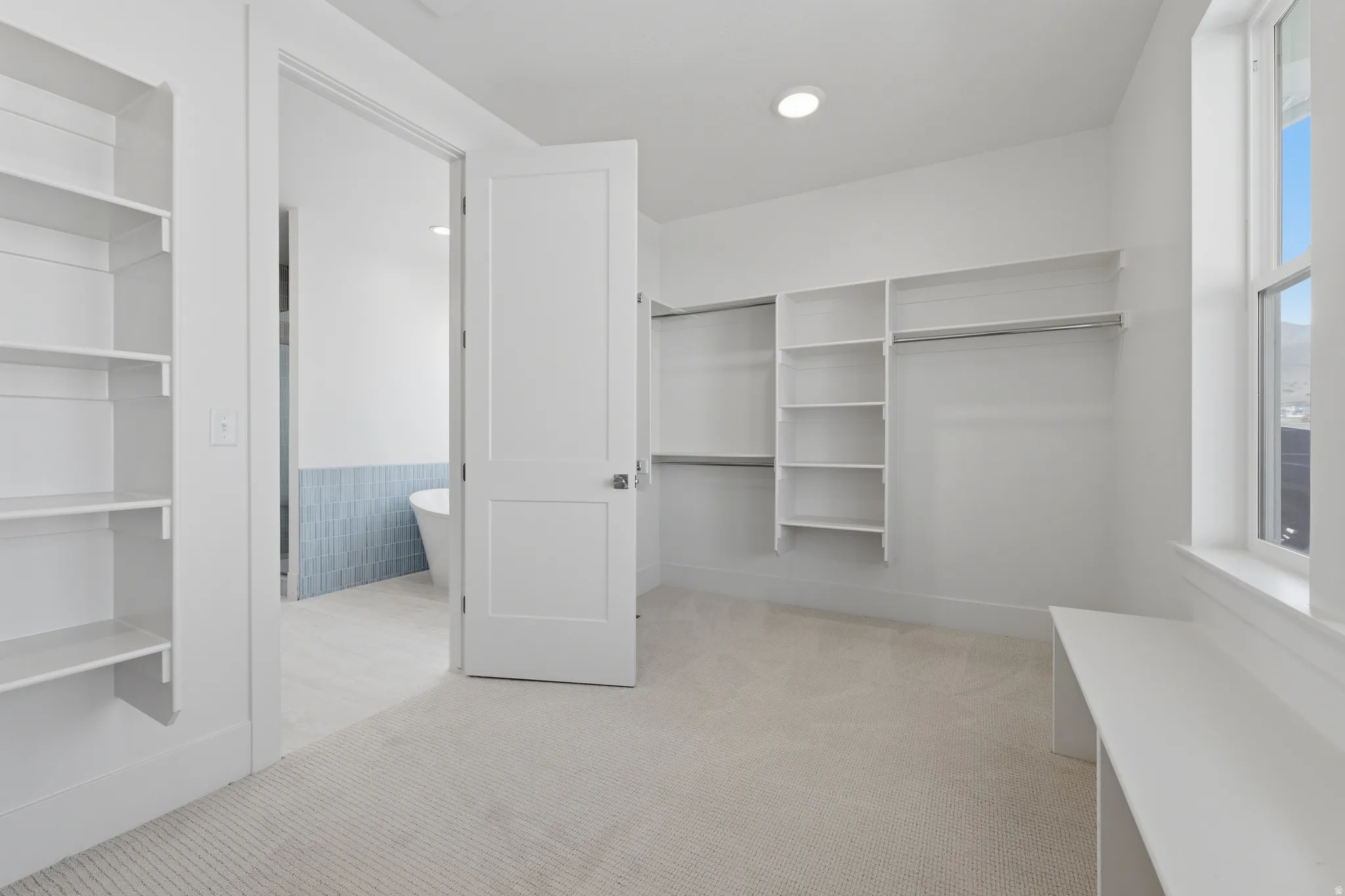 Primary Suite. Built-in shelving, integrated hanging rods, recessed lighting, window, and carpet flooring