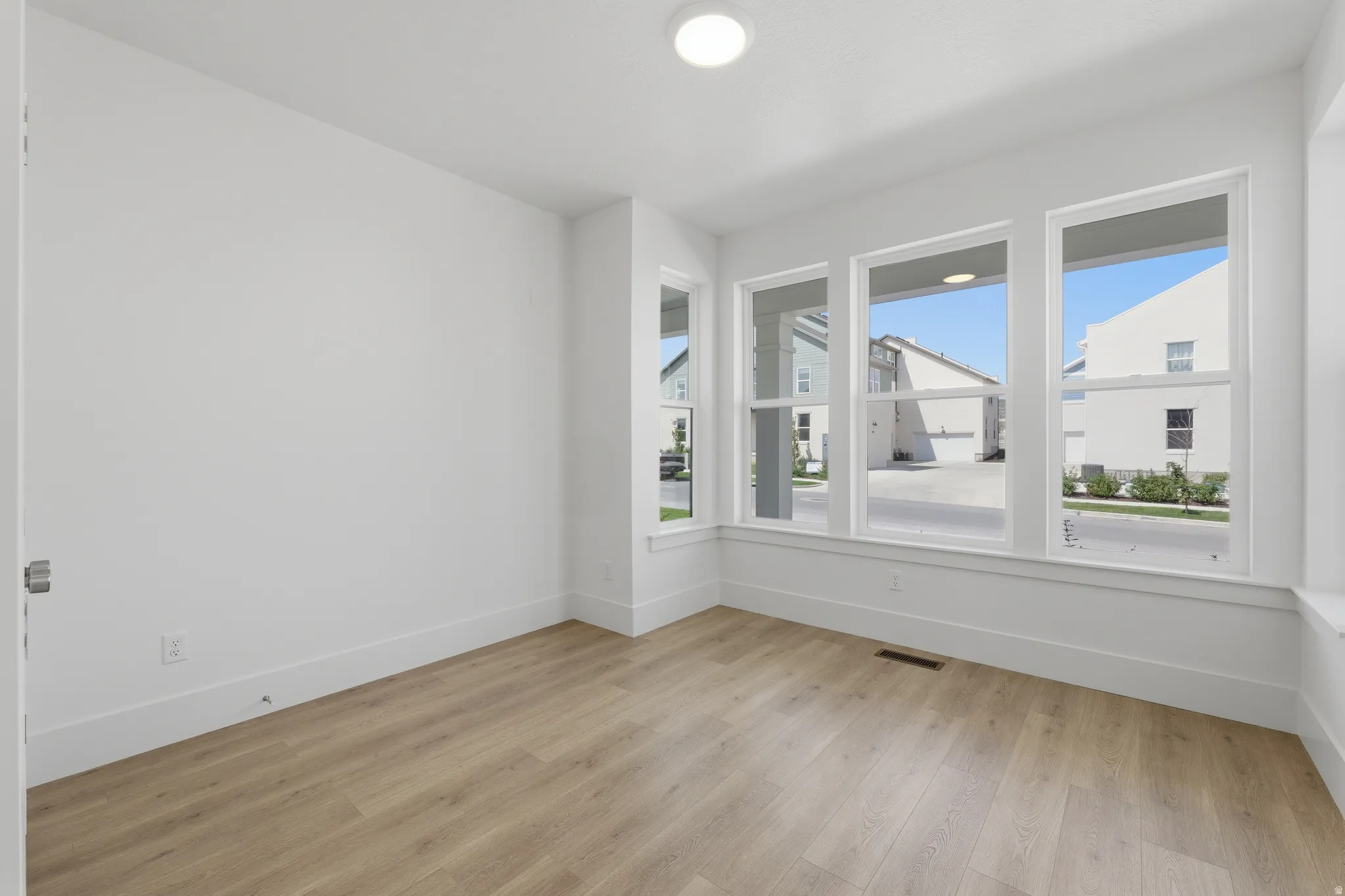 Light wood-finish flooring, white walls, and multiple large windows