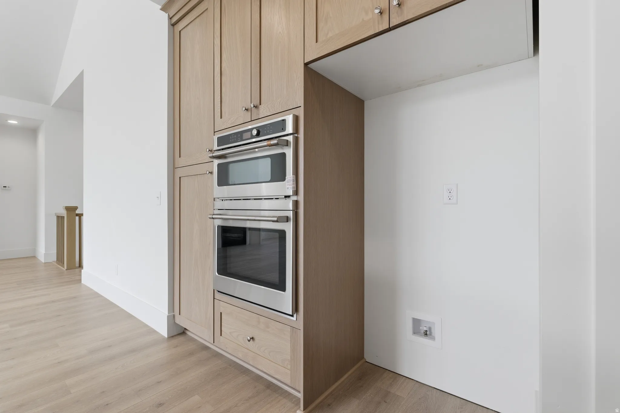 Built-in stainless steel double ovens, custom wood cabinetry with brushed nickel hardware, and wood-finish flooring