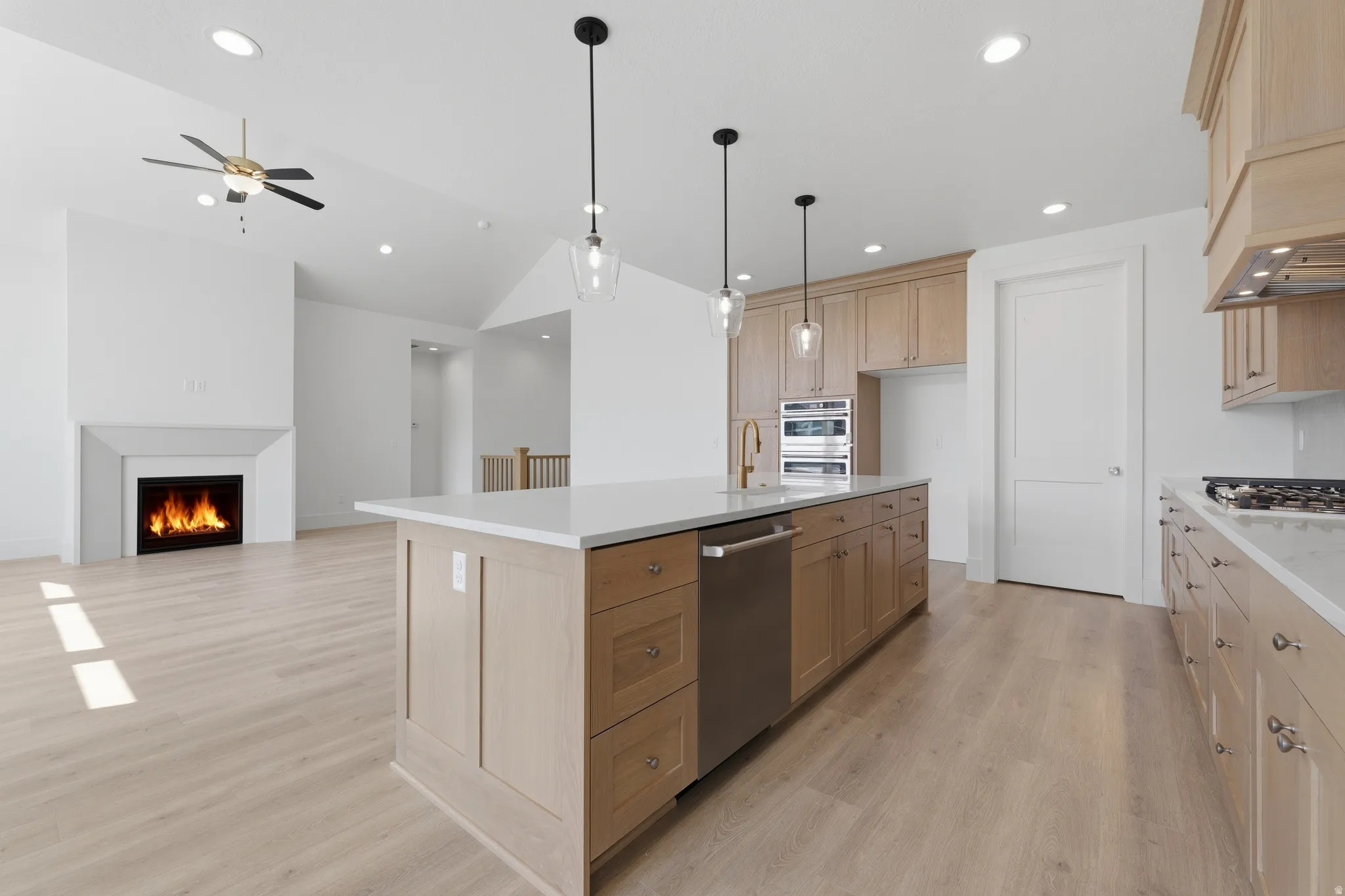Kitchen island with integrated sink, stainless steel dishwasher, and pendant lighting