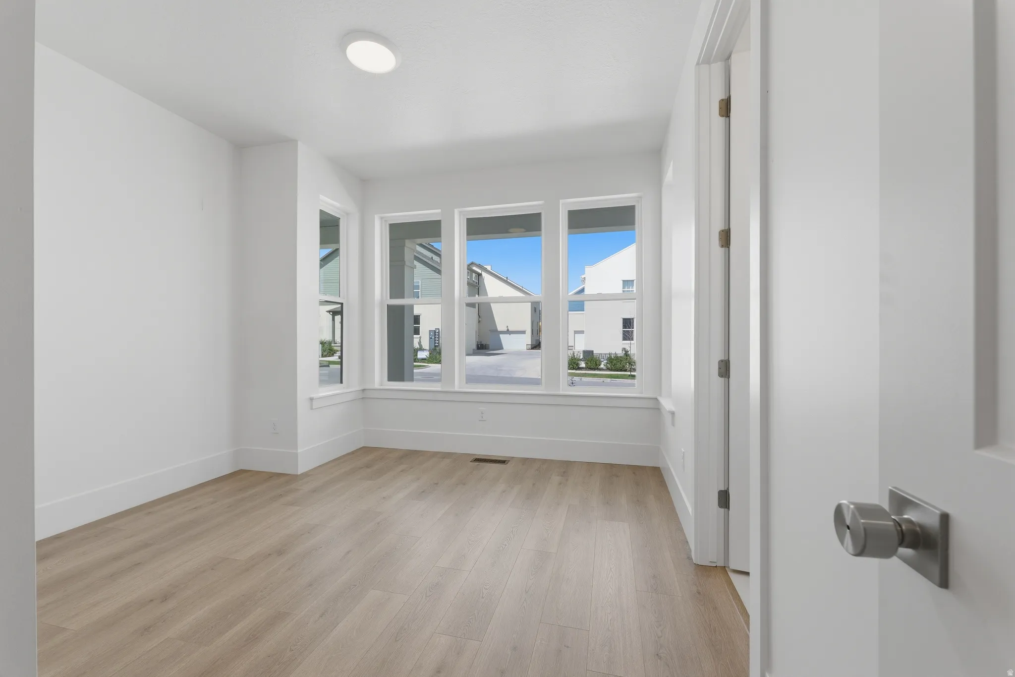 level one guest bedroom with ensuite bathroom. Neutral wall finishes, wood-finish flooring, recessed ceiling lighting, multi-pane windows, and a modern door handle