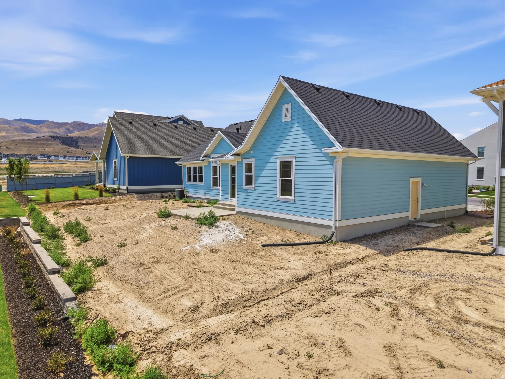 Blue siding exterior featuring a white trim, a dark shingle roof, and a concrete patio