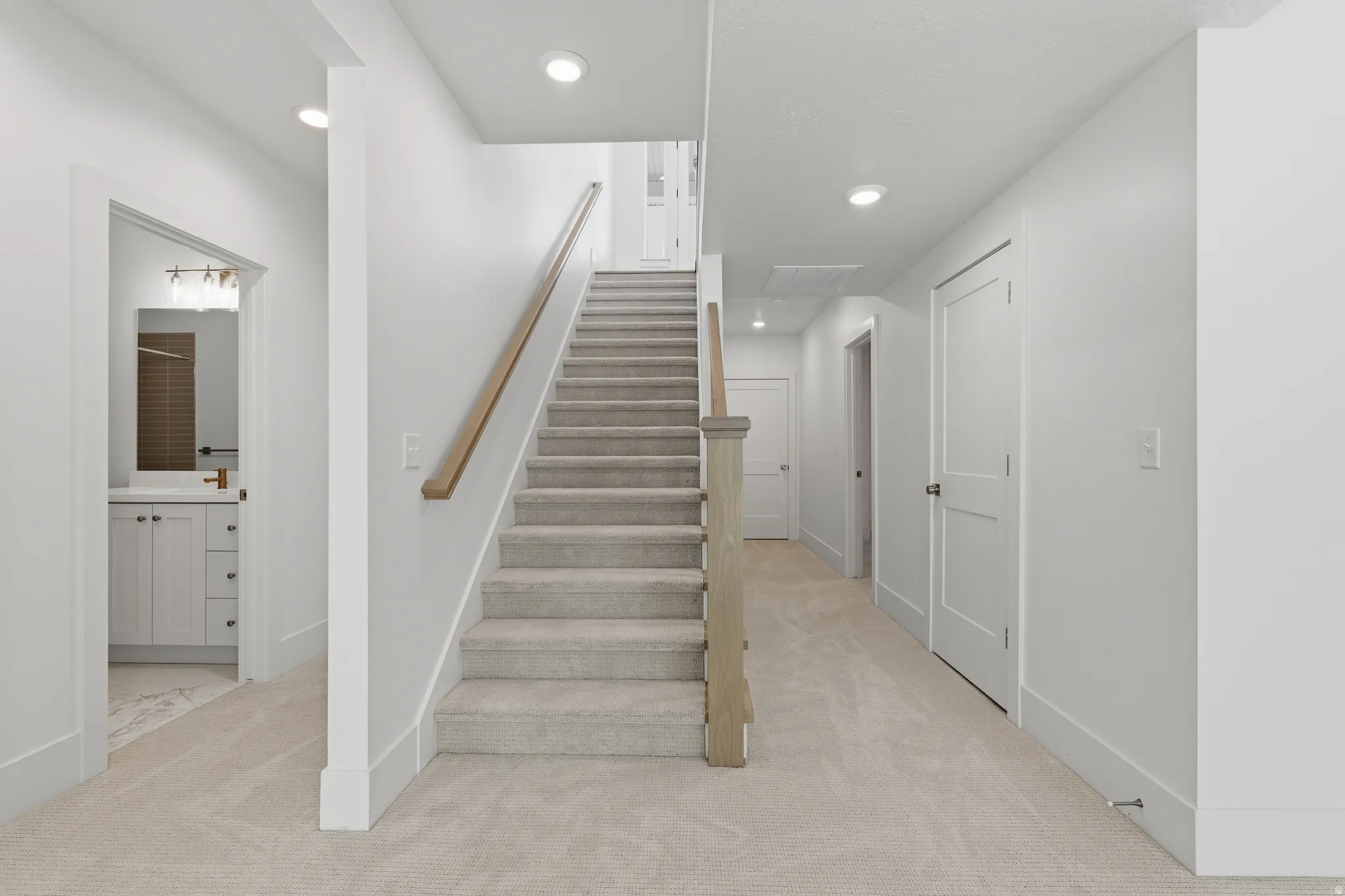 Carpeted staircase with wood railing, recessed lighting, and white paneled doors
