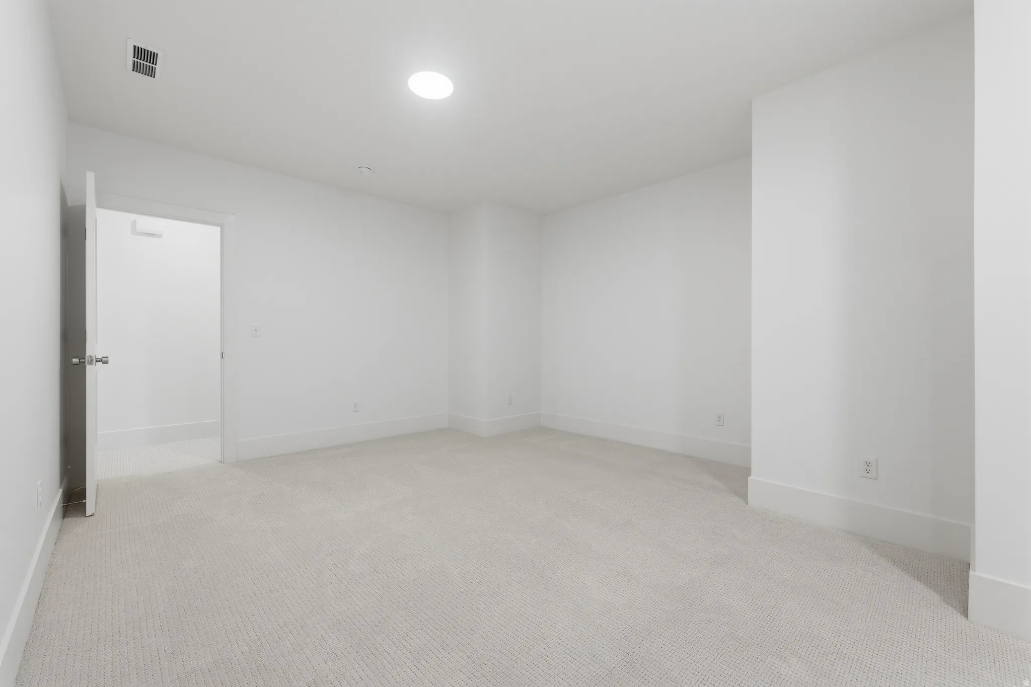 Spacious room featuring neutral wall finishes, recessed ceiling lighting, and light-toned carpet flooring