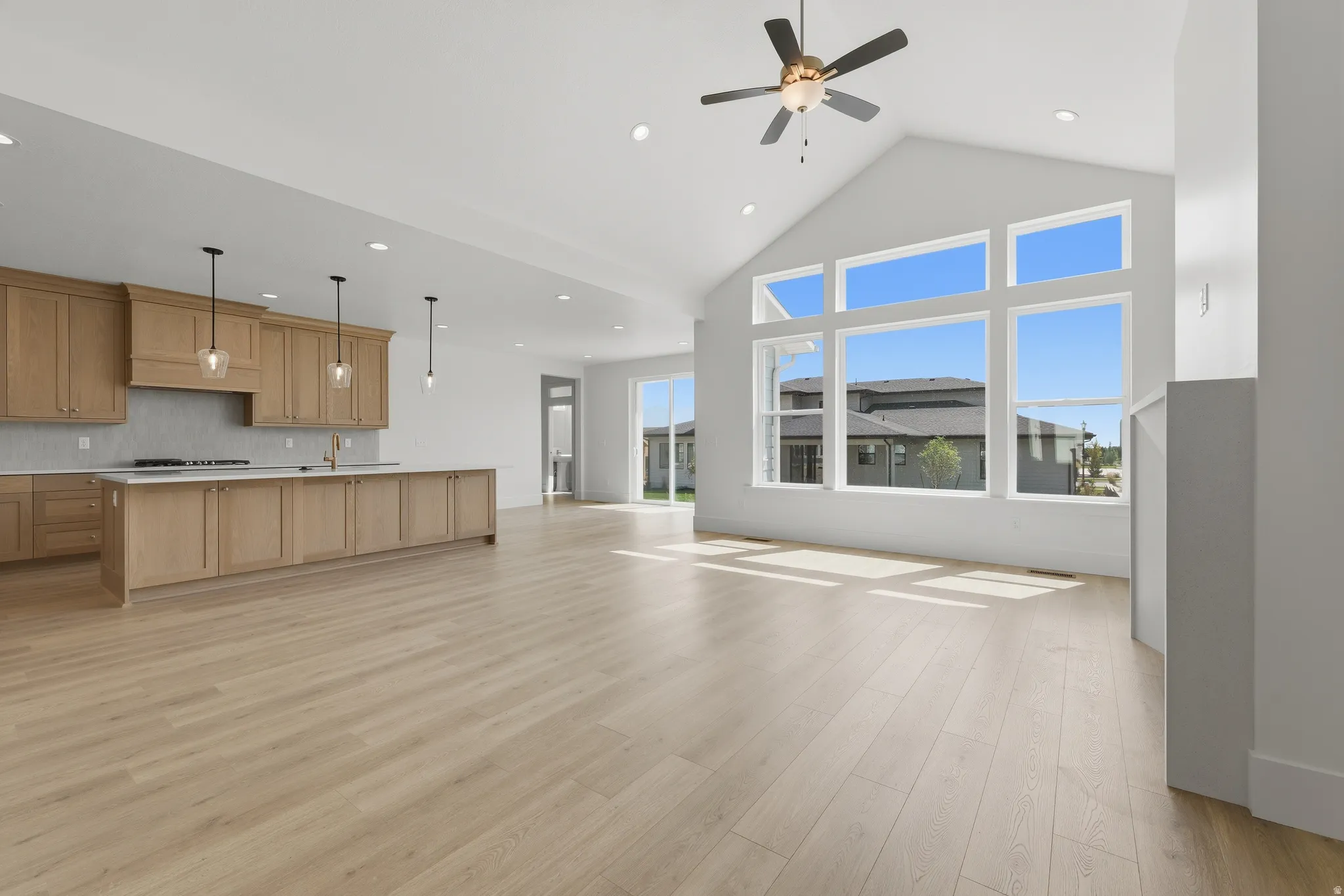 Vaulted ceiling, wood-finish flooring, custom cabinetry with a large island, recessed lighting, and expansive windows